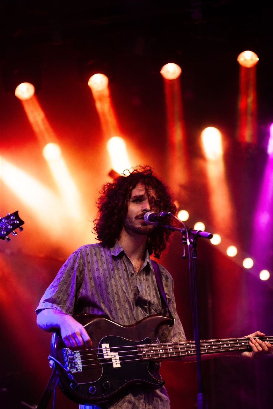 Bassist singing under red stage lights