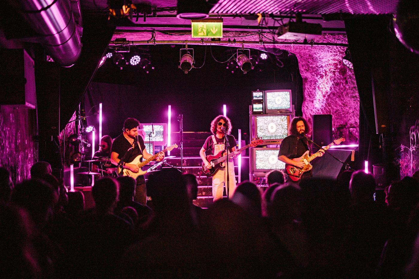 The band playing a packed club in pink light. Photo: Alina Nachtmann